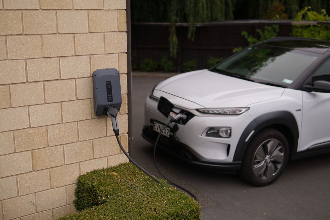 Auto eléctrico enchufado a un cargador de pared en una casa
