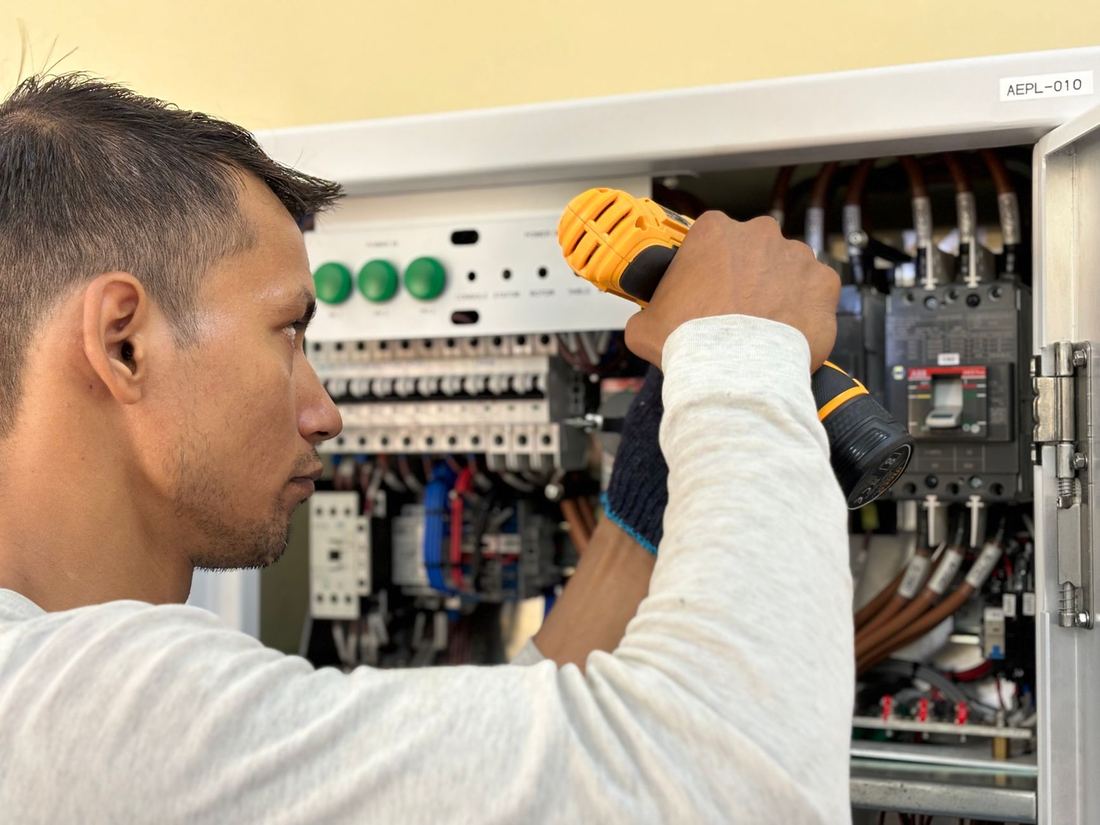 Electricista trabajando en un tablero con interruptores termomagnéticos